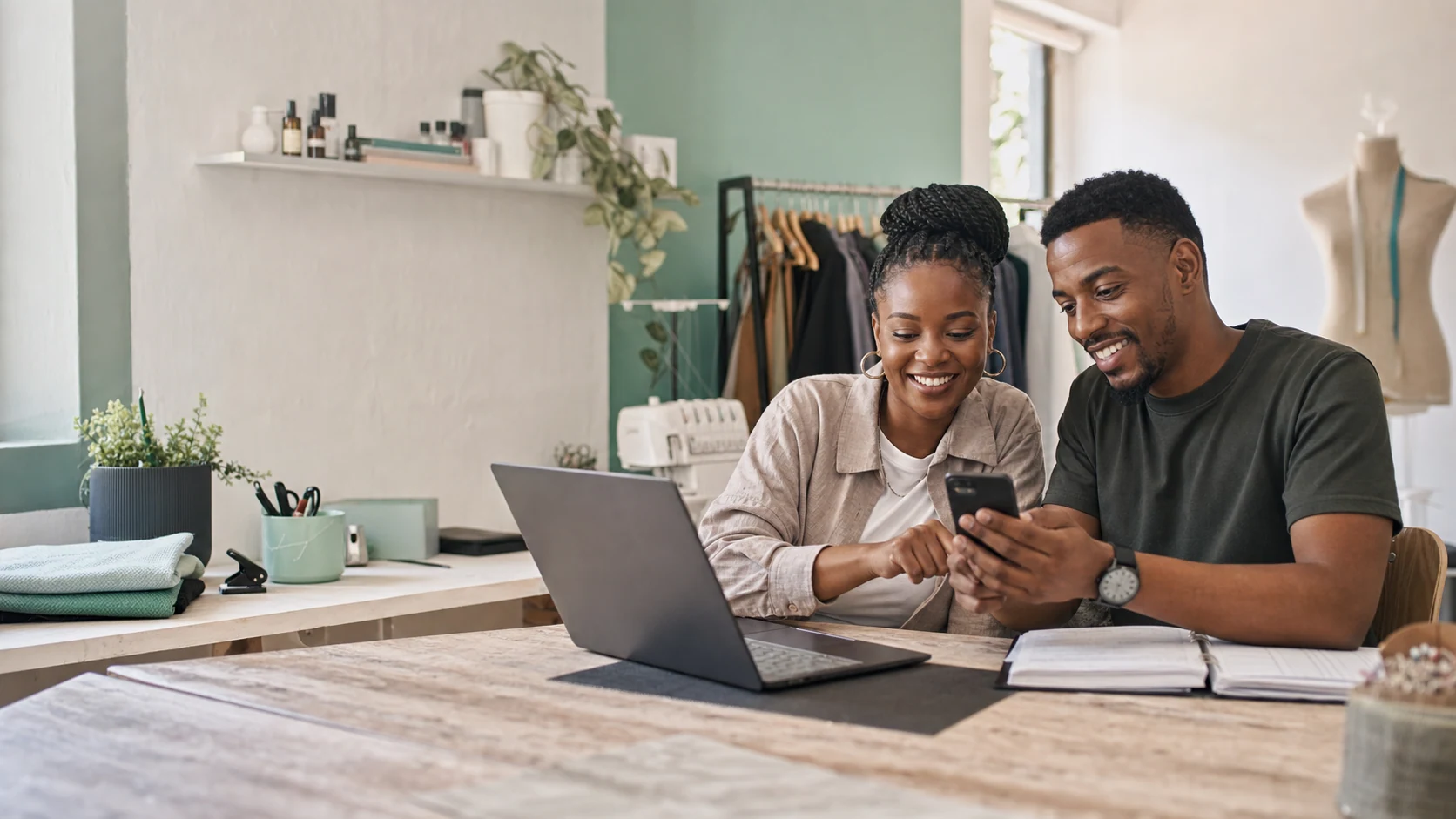 A South African small-business owner and advisor reviewing work on a phone and laptop